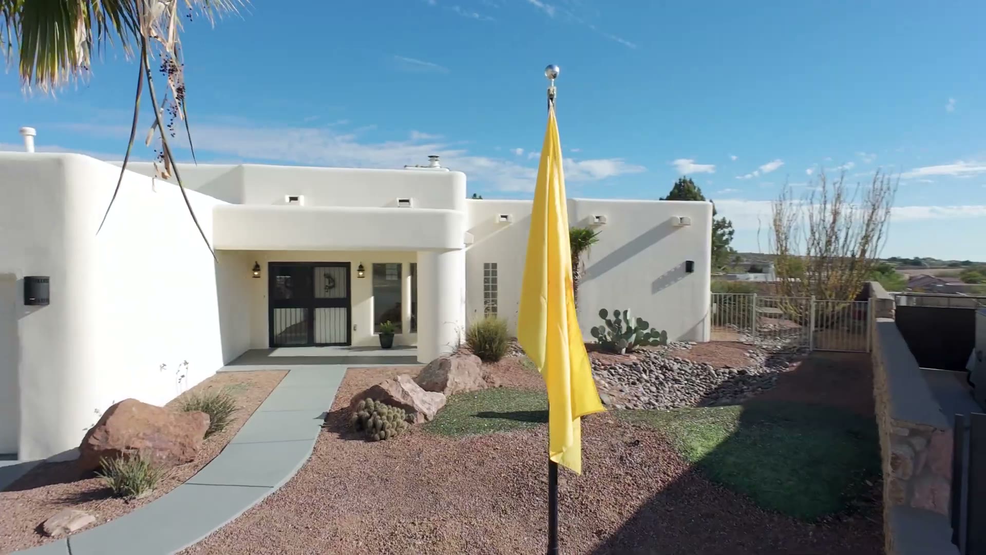White stucco Las Cruces home with the New Mexico flag, from Manny Patino listing photography
